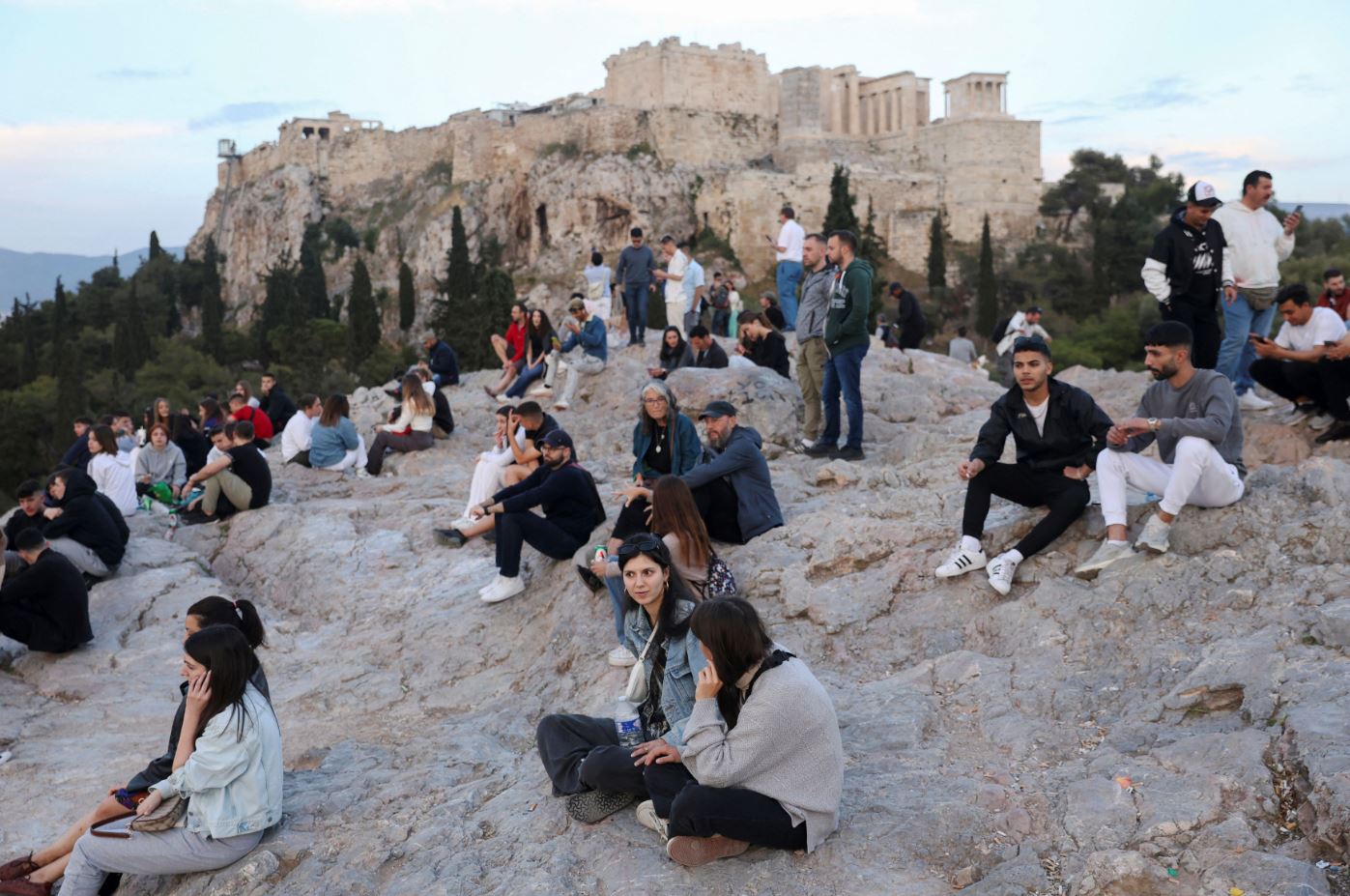 People visit the Areios Pagos hill, with the Acropolis’ Propylaea seen in the background, in Athens, May 13. [Louiza Vradi/Reuters]