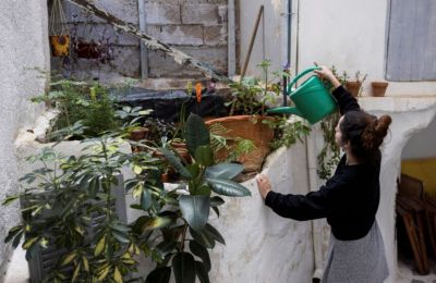 Eirini Baliaka waters her plants at her home, in Athens, May 6. [Stelios Misinas/Reuters]