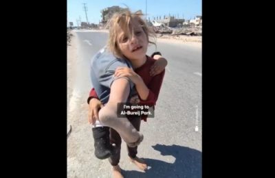 A little girl carries her little sister to find medical assistance