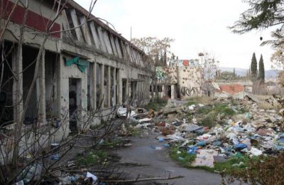 Photo of garbage dumped next to a dilapidated house in Cyprus.