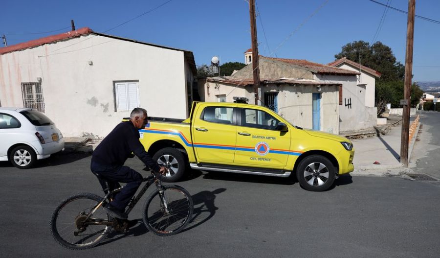 A man rides a bicycle past a Civil Defense vehicle in Akrotiri village, located near RAF Akrotiri, a British sovereign base in Cyprus that was hit by a drone early Monday. [Yiannis Kourtoglou/Reuters]