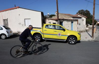 A man rides a bicycle past a Civil Defense vehicle in Akrotiri village, located near RAF Akrotiri, a British sovereign base in Cyprus that was hit by a drone early Monday. [Yiannis Kourtoglou/Reuters]